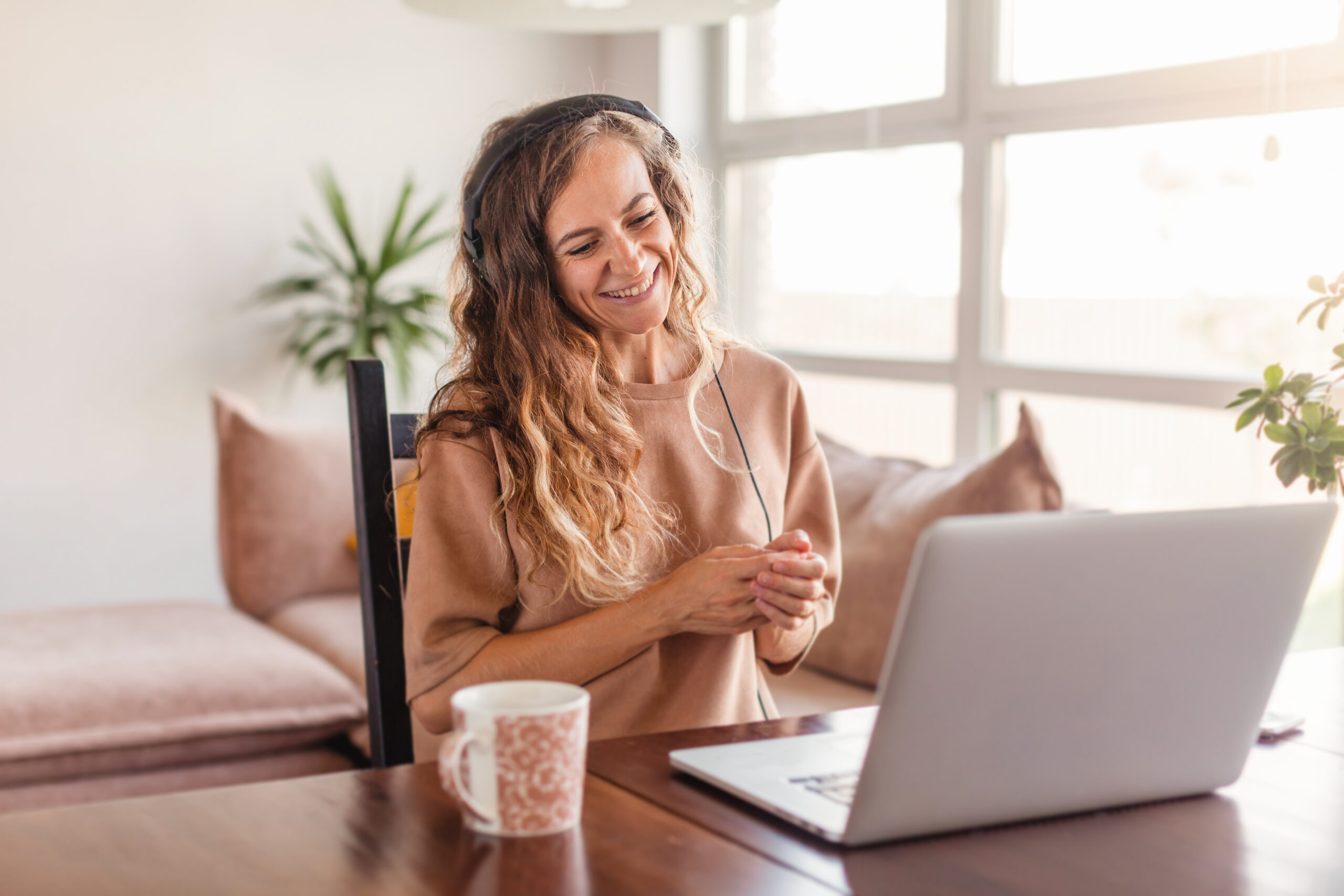 Happy casual beautiful woman working on a laptop at home. Female in headphones have video chat Smiling girl blogger learning webinar